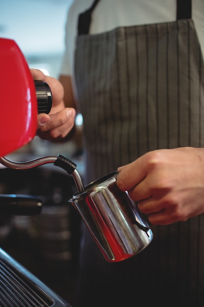 Midsection of barista pouring coffee from espresso maker at cafe