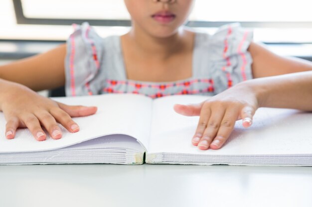 Midsection della ragazza cieca che legge il libro di braille