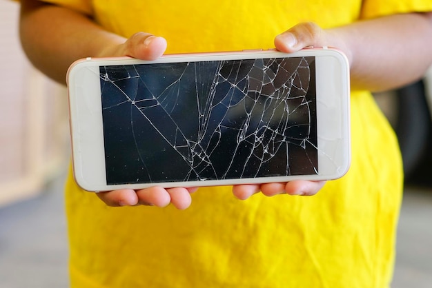 Photo midsection of boy holding damaged mobile phone