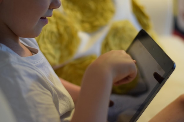 Photo midsection of boy using digital tablet at home