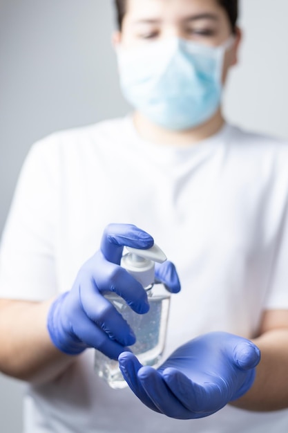 マスクをかぶった少年が消毒剤を握っている中間部分
