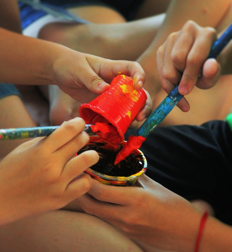 Photo midsection of boys sitting with paint and brushes