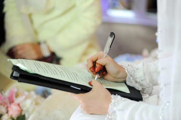 Foto sezione centrale della sposa che firma il certificato di matrimonio