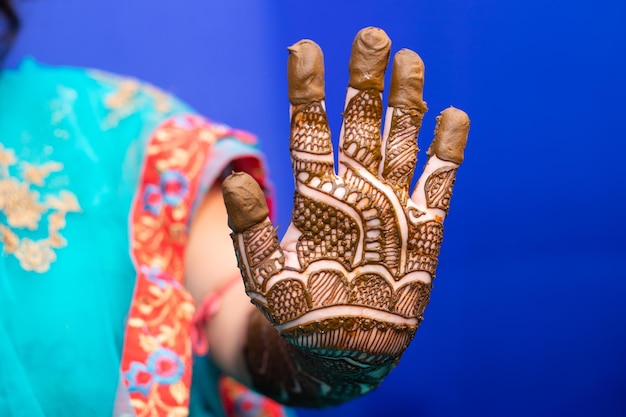 Midsection of bride with henna tattoo against blue background