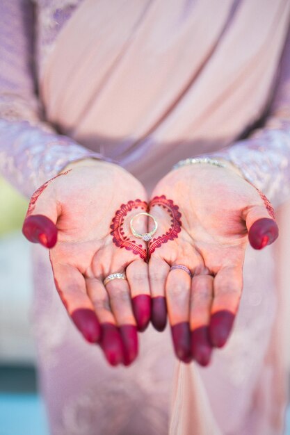 結婚指輪を握っている手にヘンナのタトゥーをつけた花嫁のミッドセクション