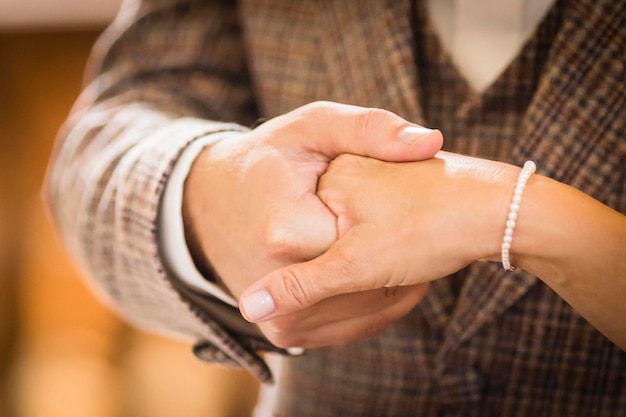 Foto sezione centrale dello sposo che tiene per mano la sposa durante la cerimonia nuziale