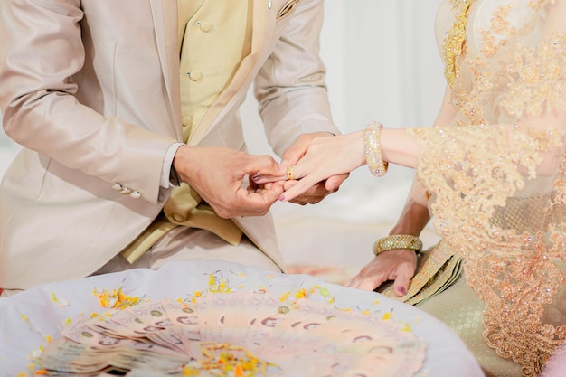 Midsection of bridegroom putting ring on bride during wedding ceremony