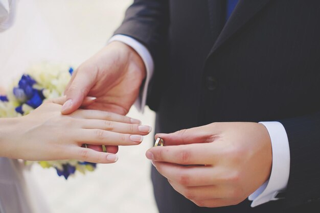 Photo midsection of bridegroom putting ring in hand of bride