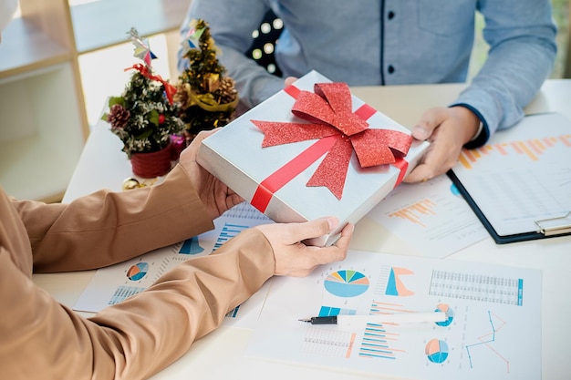 クリスマスのプレゼントを持ったビジネス同僚のミッドセクションがオフィスで文書の上に