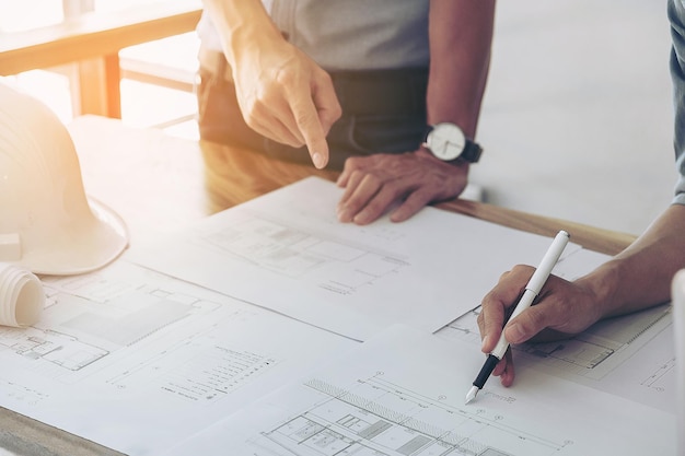 Midsection of business people discussing blueprint at desk in office