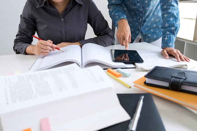Midsection of business people discussing over documents and digital tablet on desk in office