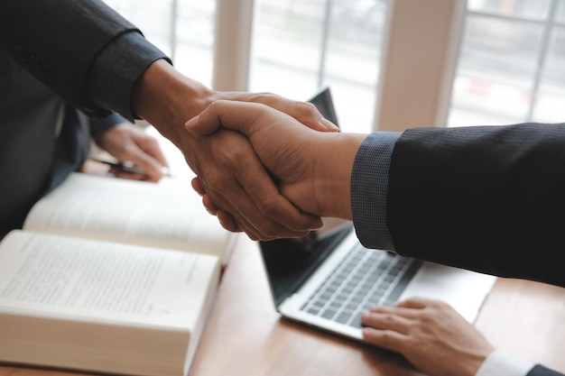 Midsection of business people shaking hands on table