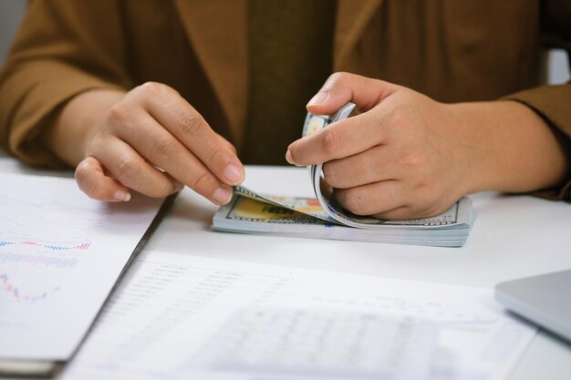 Midsection of business woman counting paper currency on desk