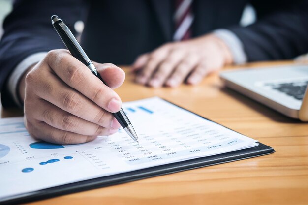 Midsection of businessman analyzing finance report on desk