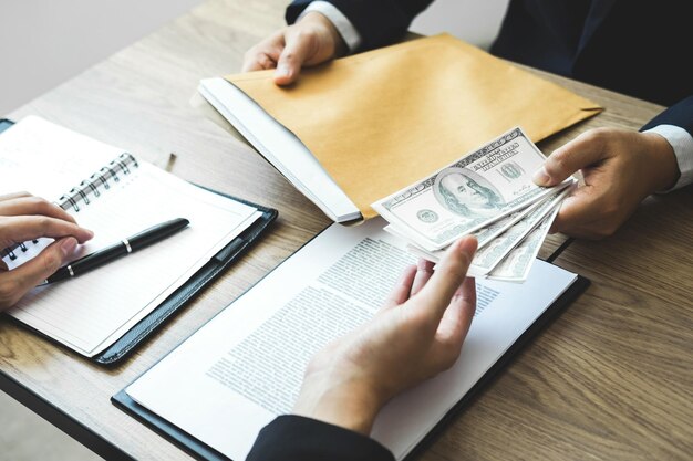 Photo midsection of businessman bribing coworker at desk in office