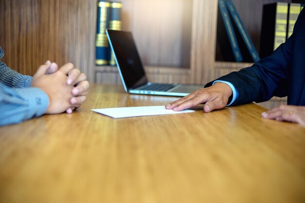 Photo midsection of businessman giving envelope to candidate on table