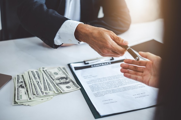 Photo midsection of businessman giving pen to businesswoman