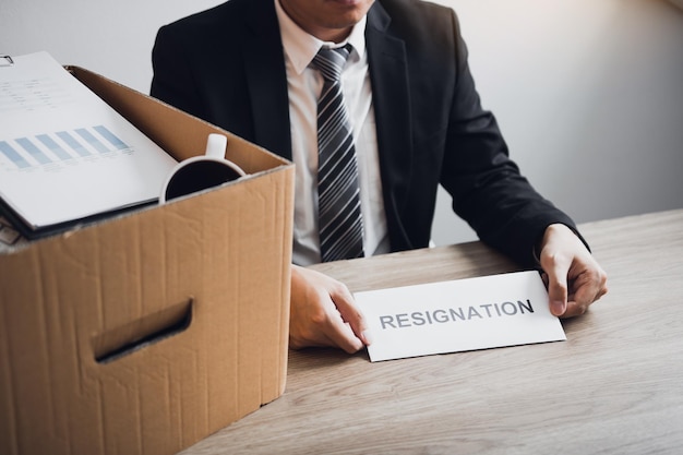 Midsection of businessman giving resignation letter in office