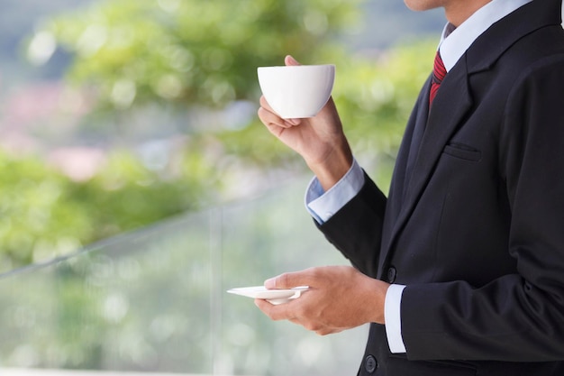 Midsection of businessman having coffee in cup while standing outdoors