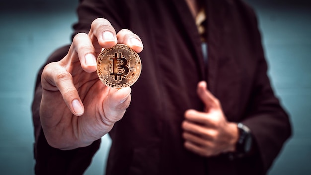 Foto sezione centrale di un uomo d'affari che tiene in mano il bitcoin mentre è in carica