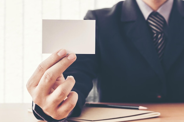 Midsection of businessman holding blank card