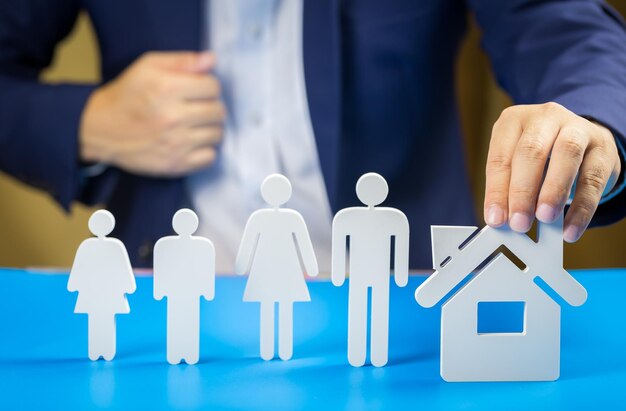 Midsection of businessman holding model house on table