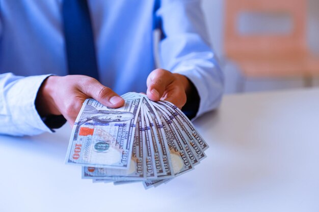 Midsection of businessman holding paper currency over office desk