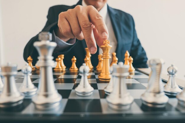 Midsection of businessman playing chess on table against wall in office