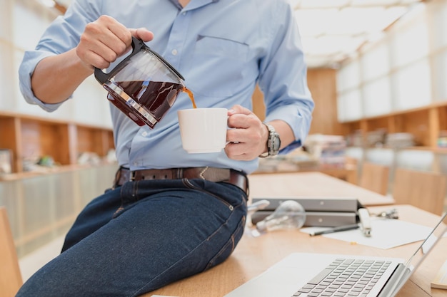 Photo midsection of businessman pouring coffee in cup at office