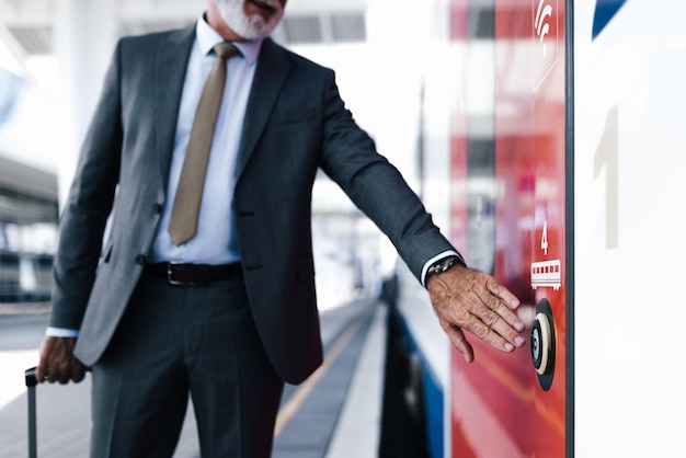 Midsection of businessman pushing open door button of a train at the train station platform