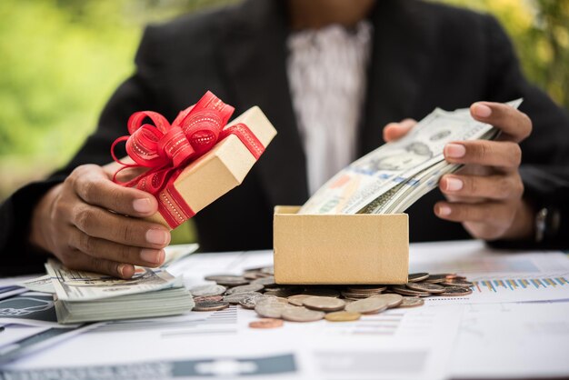 Photo midsection of businessman putting money in gift box