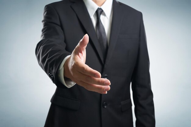 Midsection of businessman reaching for handshake against gray background