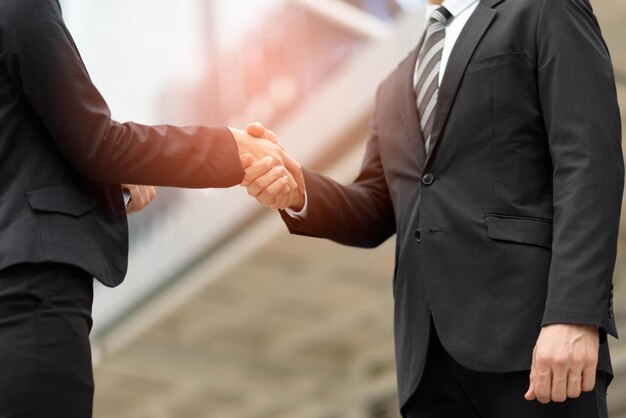 Midsection of businessman shaking hands outdoors