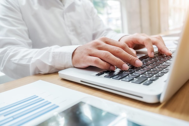 Midsection of businessman using laptop on desk in office