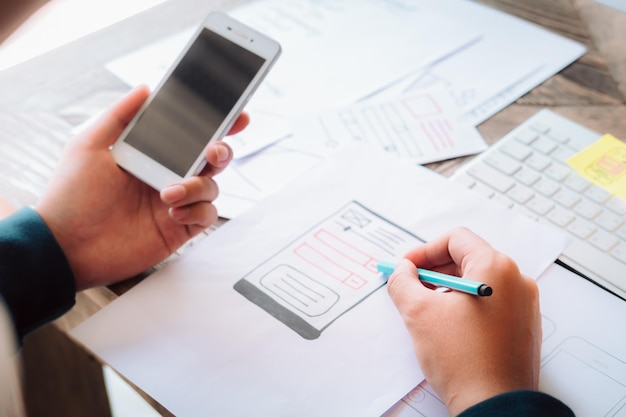 Photo midsection of businessman using mobile phone while writing in paper on table