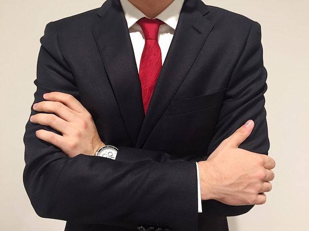 ベージュ色の背景に腕を交差させたビジネスマンの中間部分