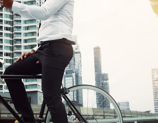 Photo midsection of businessman with bicycle standing against building in city