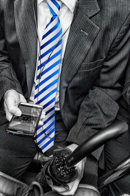 Photo midsection of businessman with blue necktie using smart phone