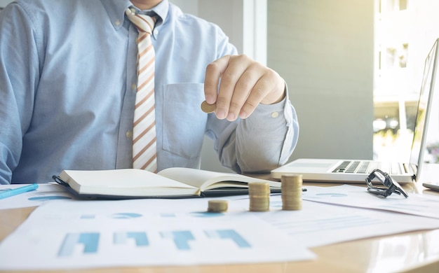 Midsection of businessman with coins at desk