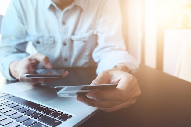 Midsection of businessman with using mobile phone and credit card in office