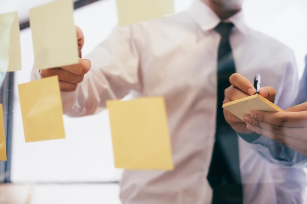 Photo midsection of businessman writing in adhesive note at office