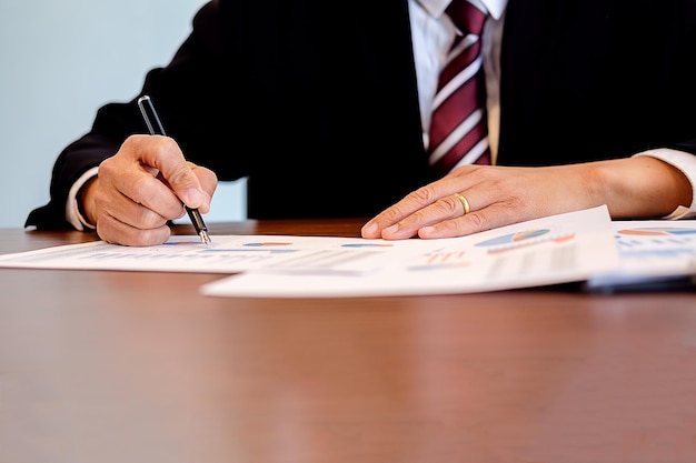 Midsection of businessman writing on document at desk