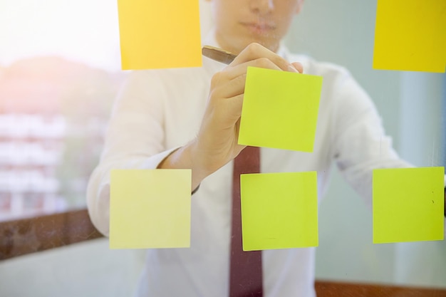 Midsection of businessman writing on sticky notes