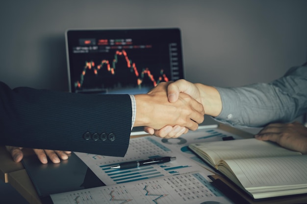 Photo midsection of businessmen shaking hands over graph on table