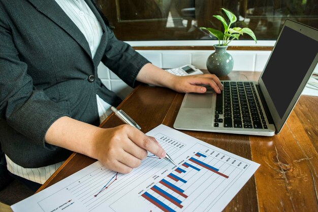 Midsection of businesswoman analyzing graphs on desk in office