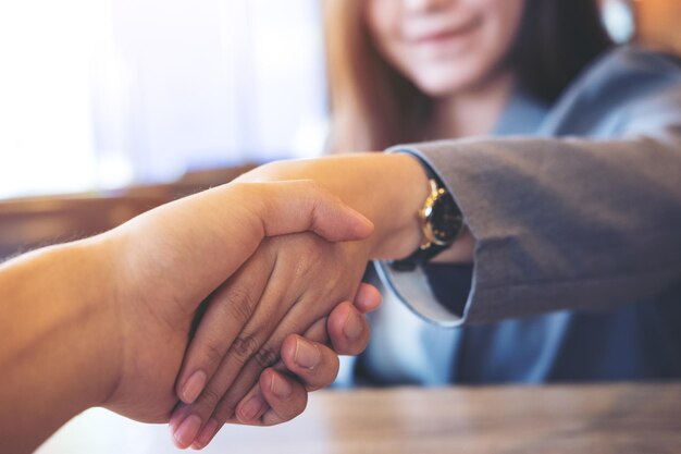 Foto sezione centrale di una donna d'affari che stringe la mano a un collega in ufficio