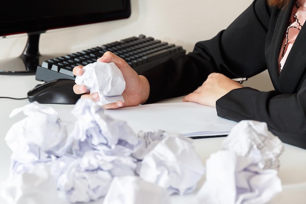 Midsection of businesswoman holding crumpled paper while working in office