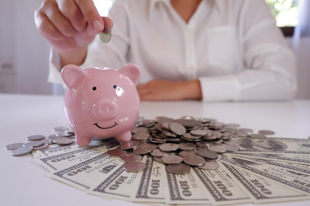 Photo midsection of businesswoman inserting coin in piggy bank at office