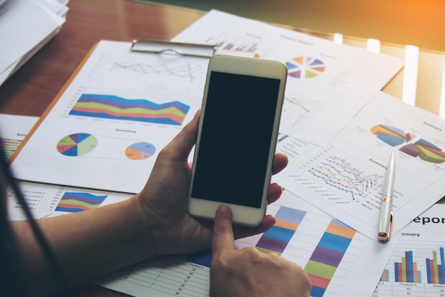 Midsection of businesswoman using mobile phone at desk in office