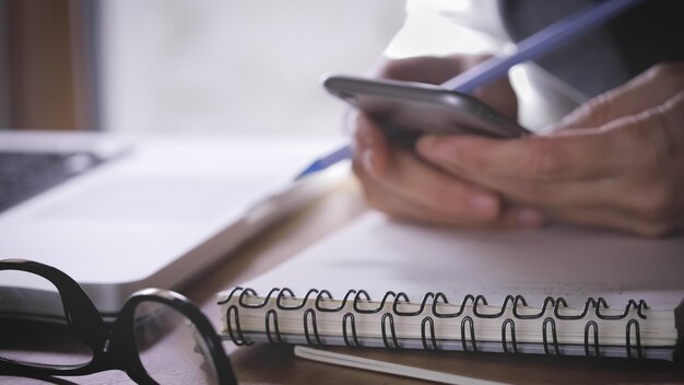 Photo midsection of businesswoman using mobile while writing in diary